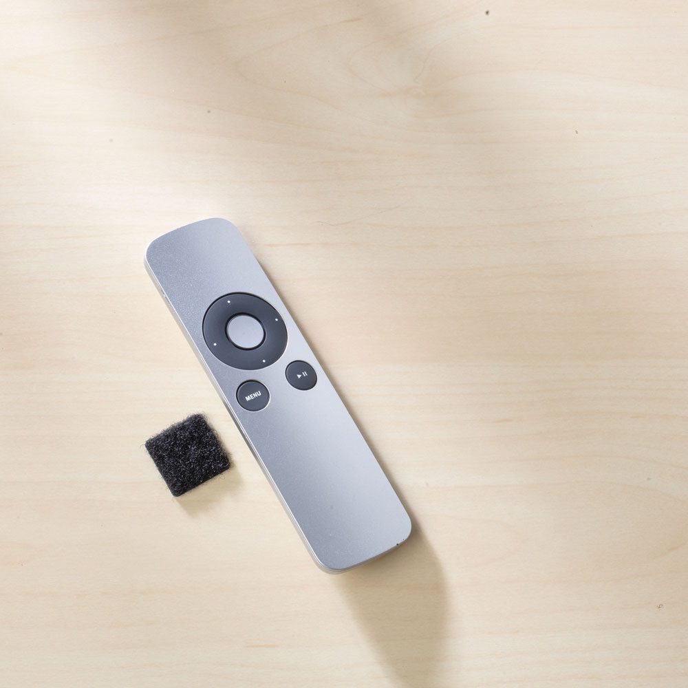 Remote on table with double-sided square fastener.