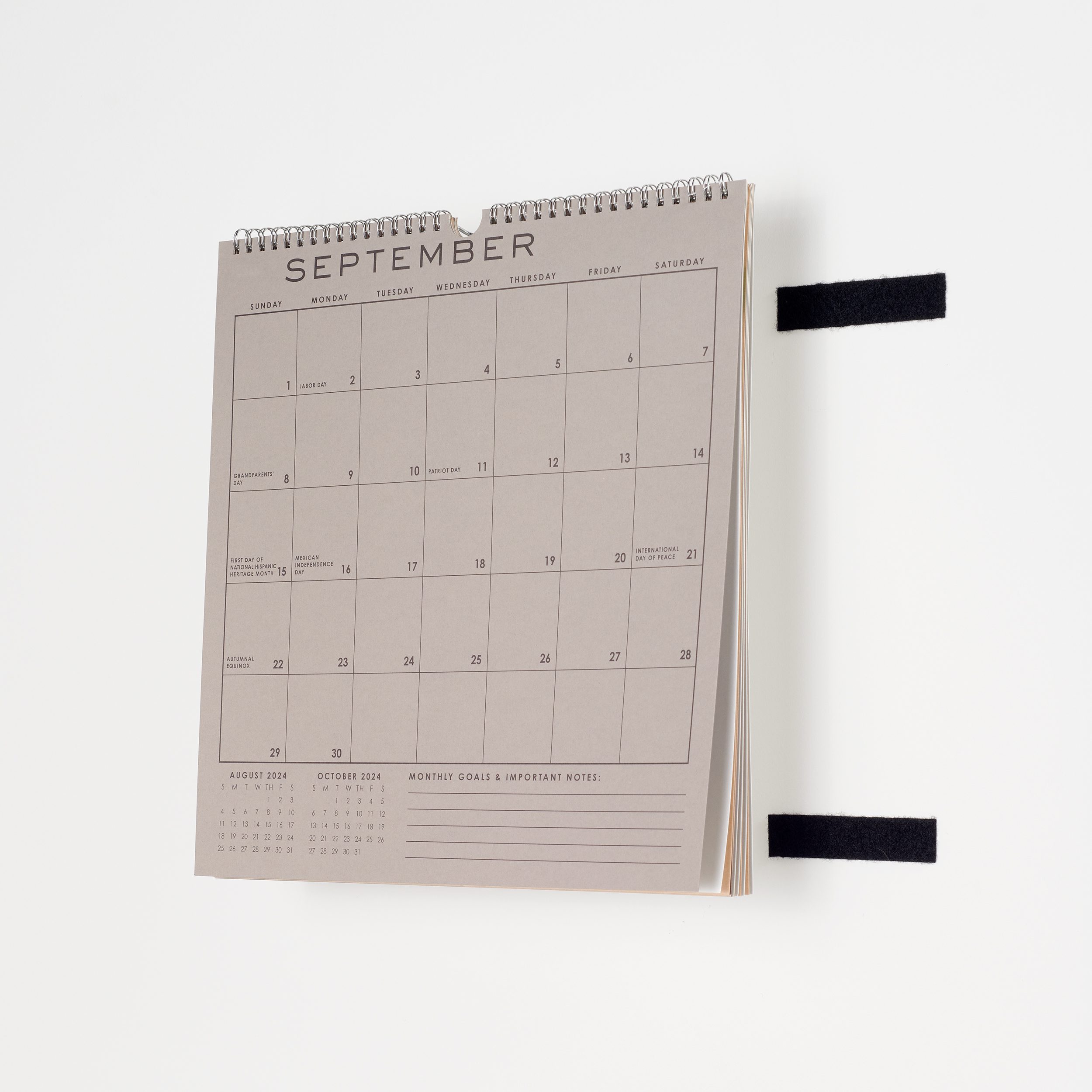 Calendar being stuck to wall with sticky back hook and loop tape.