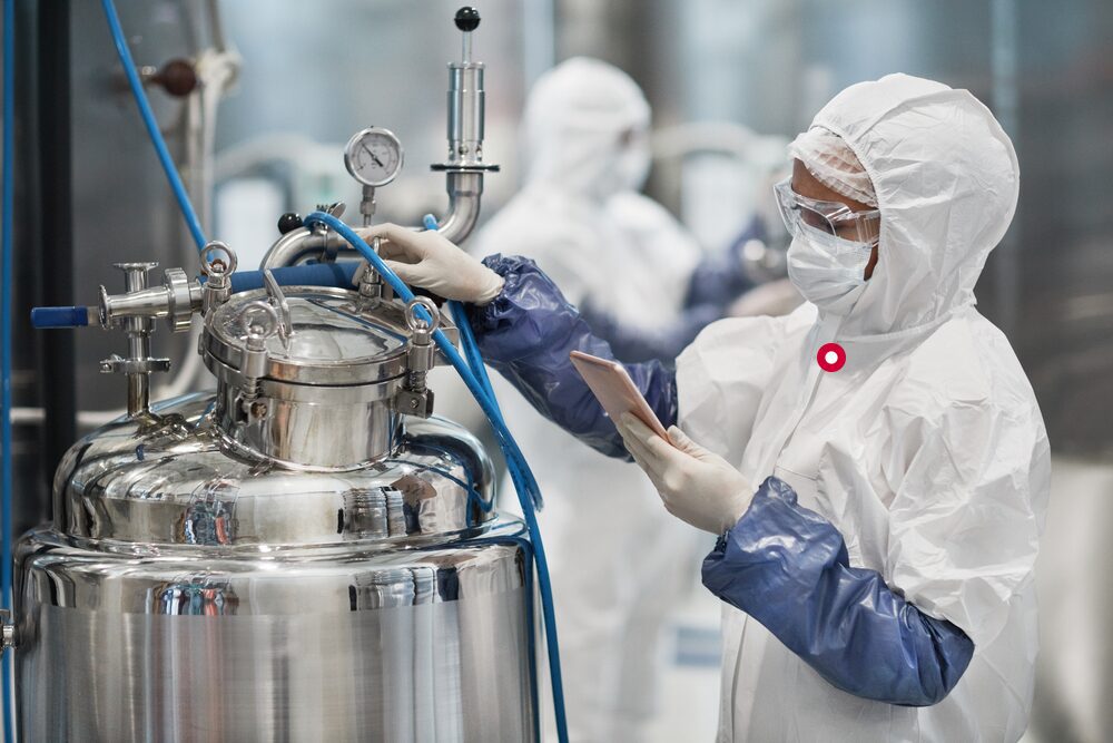 Female worker wearing protective suit while operating equipment at modern chemical plant.