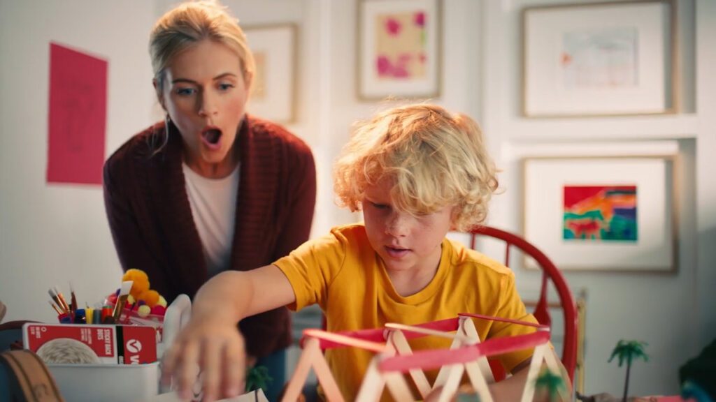 A child and a parent doing a craft project with popsicle sticks using VELCRO® Brand products.