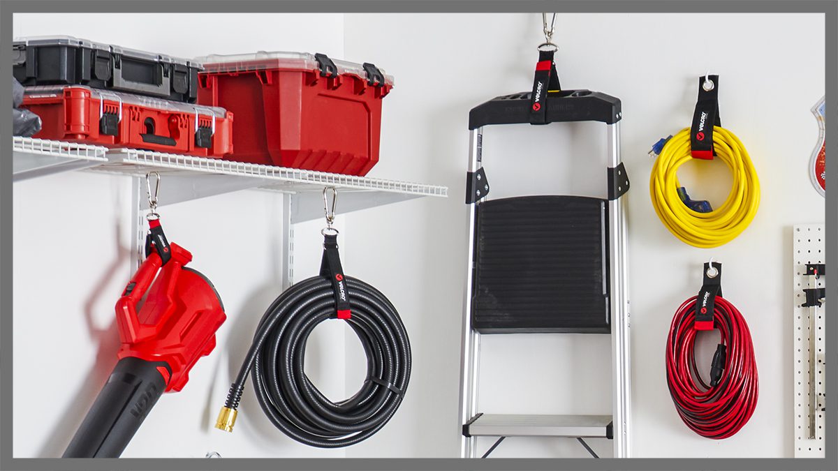Garage tools and outdoor equipment organized with VELCRO® Brand fasteners, featuring extension cords, leaf blower, hose and ladder secured with durable hook and loop straps for efficient storage.