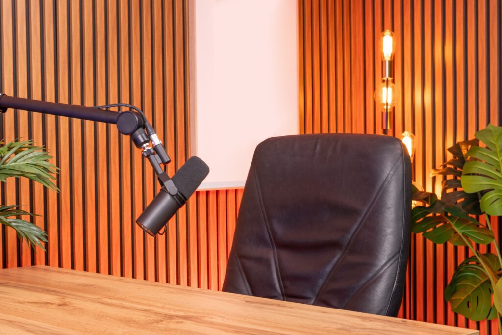 Acoustic wall paneling behind a podcast desk with a microphone in a modern studio setup.