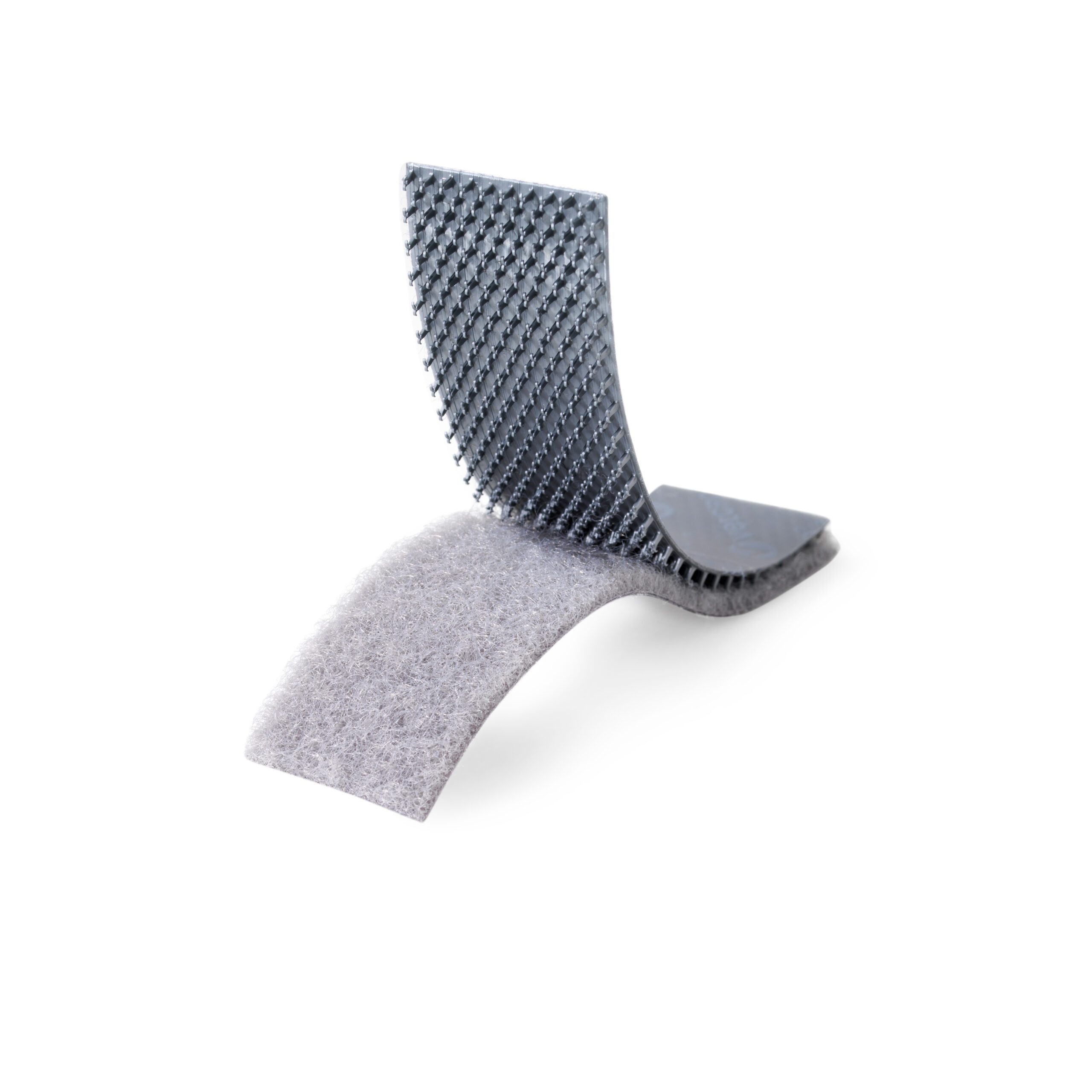 Close-up image of a VELCRO® Brand hook and loop fastener with the hook side facing up and the loop side facing down, demonstrating the product's texture and fastening mechanism.