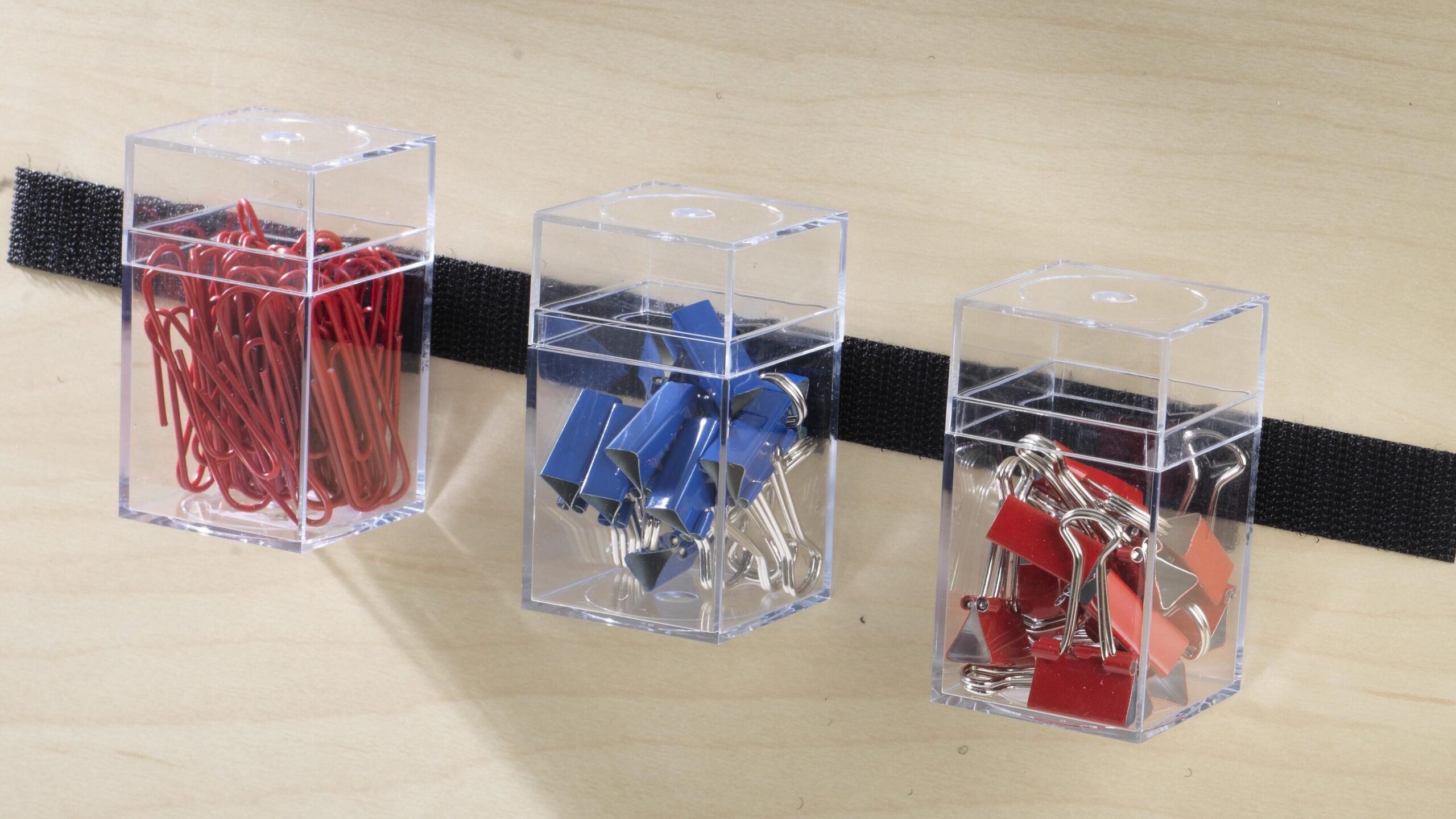 Office supplies stuck to wall using black VELCRO® Brand strips with adhesive.