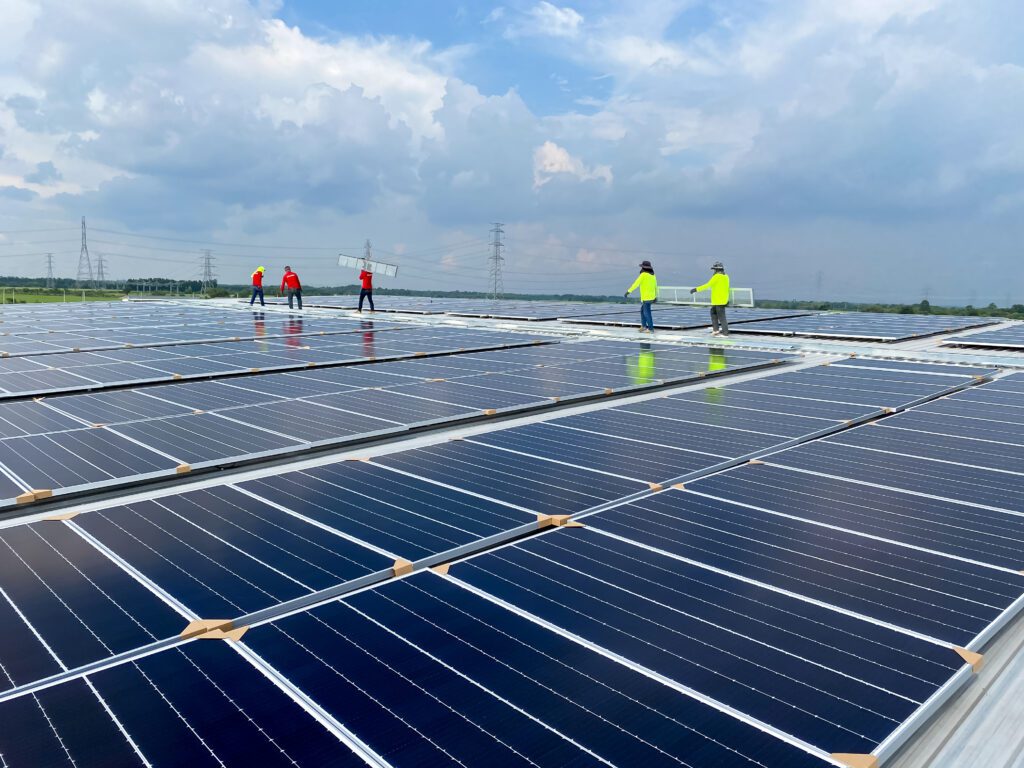 Five people installing solar panels on a roof using VELCRO® Brand fasteners.