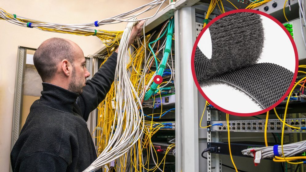 Man tidying cables in a data management center using VELCRO® Brand self-engaging fasteners.