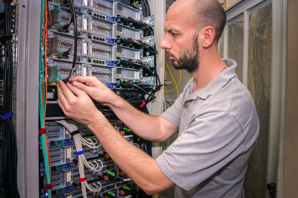 Data center cable management: technician routing cables at server rack equipment during MACs and troubleshooting.