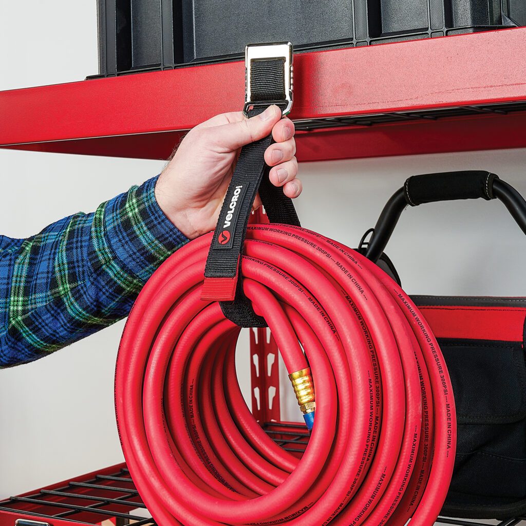 VELCRO® Brand EASY HANG™ Magnetic Strap hanging hose to red metal shelf.