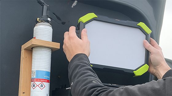 A worker mounts an LED work light inside a service van to keep tools and equipment organized.